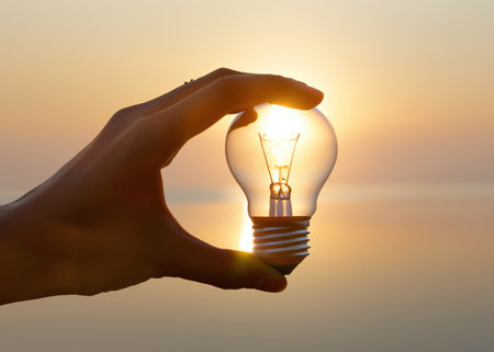 "Enlightened Mind: Hand Holding Glowing Light Bulb of Invention" - Delve into the world of bright ideas and ingenuity with this evocative image of a hand holding a glowing light bulb.の素材