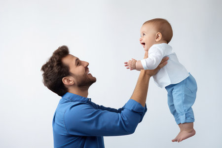 "Dad Lifting Baby with Joy - A heartwarming moment as a young father lifts his baby overhead."の素材