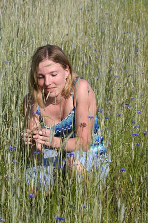 Young woman with blue flower on meadowの写真素材