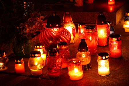 Closeup of votive candles lit on tombstone