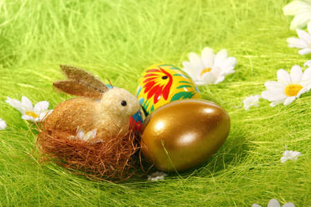 Easter Eggs and rabbit sitting on grass field with blue sky background