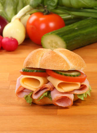Crusty white roll filled with ham and salad on wooden boardの写真素材