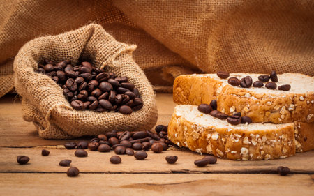 Close up  of Coffee beans and bread setup on shabby wooden background.
