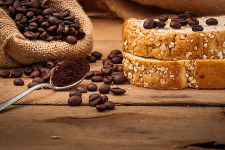 Close up  of Coffee beans and bread setup on shabby wooden background.の写真素材