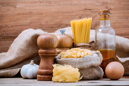 Italian food concept various pasta with olive oil flavored and seasoning  set up with hemp sack and wooden background.の写真素材