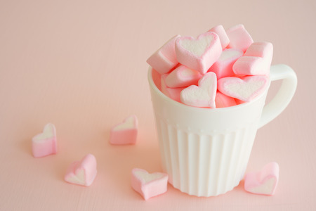 Fluffy pink heart marshmallow in vintage cup on pink backgroundの写真素材