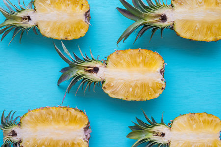Flat lay of half sliced organic pineapple on blue wooden background, tropical summer holiday...