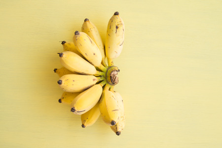 Flat lay of banana bunch on yellow background - Creative ideas summer holiday conceptの写真素材