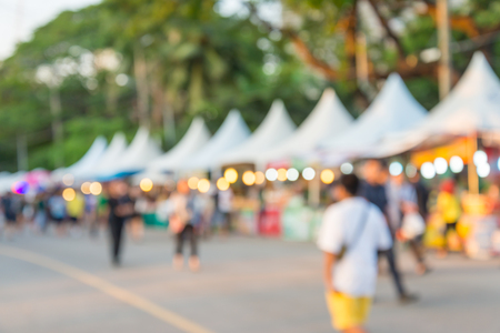 Blurred image of people in day market festival in city park backgroundの写真素材