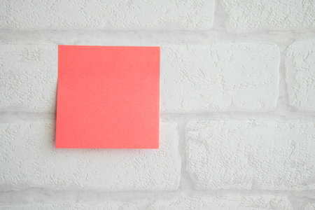 Red paper note on white wallpaper brick pattern background