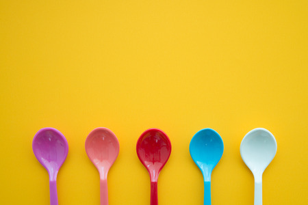 Colorful spoons and dish on yellow backgroundの写真素材