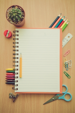Top view of education and business supplies on wooden table with empty space notepad - Retro filter effectの写真素材