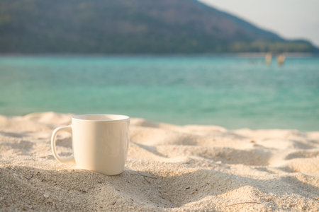 White coffee cup on beach with warm sunlight - Selective focusの写真素材