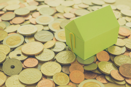 Green paper house on heap of vary country coins background - ideas house real estate concept , Vintage filter effectの写真素材