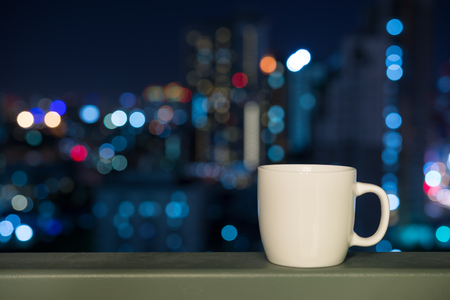 White cup over city night bokeh backgroundの写真素材