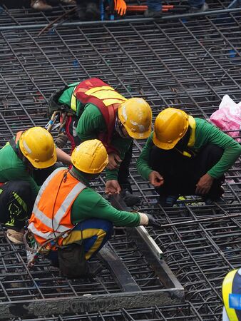 a goup of worker is working on high contruction area, with iron wire structureの写真素材