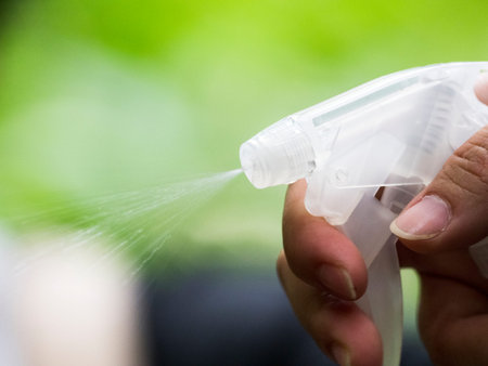 woman use white plastic spray water in garden with green blur backgrond