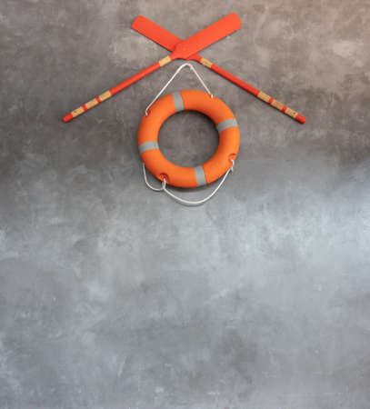 orange lifebuoy and two oars on gray wallの写真素材