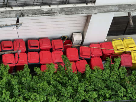 many red plastic bin stock in garden near the wallの写真素材
