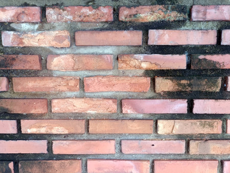A close up showing an old brick wall that is rough and sturdy, making us feel its age and stories it holds. its textured surface displays sense of resilience and timelessnessの写真素材