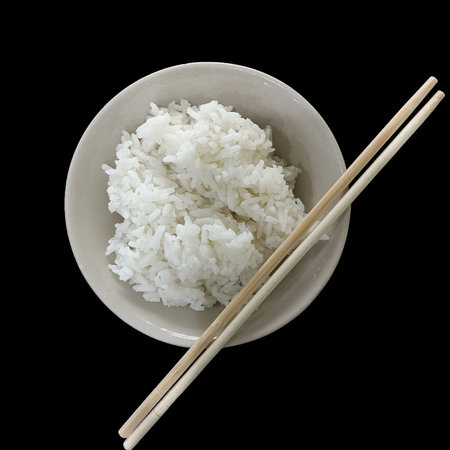 Steamed white rice in ceramic bowl with wooden chopsticks, simple comforting meal ready to eat and evoke homely warmthの写真素材