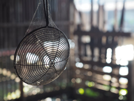 Old wire strainer spiderweb dust rustic kitchen metal utensil soft sunlight bokeh background vintage mood hangingの写真素材