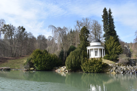 Beautiful nature with a small lake and a waterfall with a white chapel at World Cultural Heritage Hercules in Kassel, Wilhelmshoehe, Germanyの写真素材