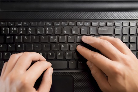 Fingers pressing keyboard key on laptop. Hands with computerの写真素材