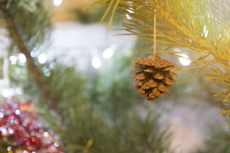 Merry Christmas background. Cone on decorated pine tree closeup over blurred garland lights shinigの写真素材