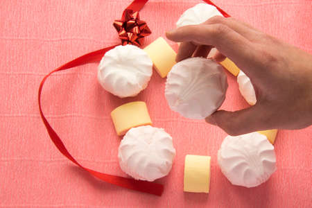 Hand hold white zephyr with colorful marshmellows in backgroundの写真素材