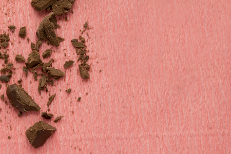 Cracked or broken chocolate parts on pink textured background with copy space.の写真素材