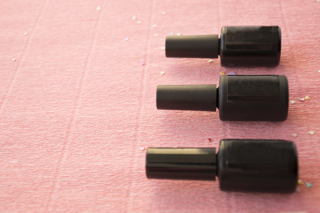 Pink background with black bottles of finger nail polish or gel border for copy space.の写真素材