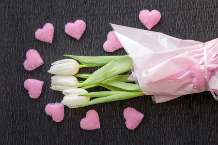 Valentines Day or Women Day holiday background with bouquet of fresh tulips decorated with pink hearts.の写真素材