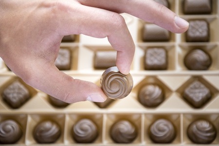 Human fingers keeping round chocolate sweetmeatの写真素材