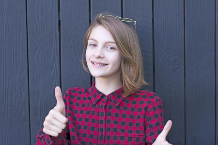 Pretty teenage girl promoting something with thumbs up gestureの写真素材
