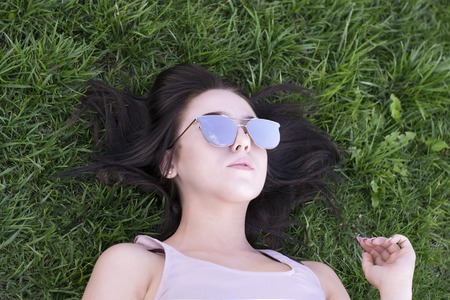 Charming model resting in park with fashion sunglassesの写真素材