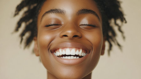 Close-up of a person smiling with bright, white teeth, showcasing the perfect alignment and radiance of their smile against a neutral background.の素材