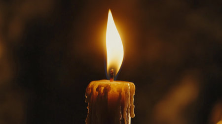 Close-up of a candle flame flickering softly in the dark, casting a warm, golden glow and creating a serene, peaceful ambiance.の素材