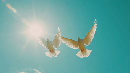 An enchanting shot of two doves in flight against a bright blue sky, their wings spread wide, symbolizing freedom and unity in natureの素材