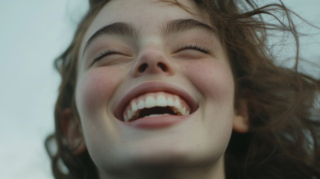A detailed shot of a young woman laughing or smiling with her eyes crinkling, capturing the joy and spontaneity of her expression and the warmth of her personality.の素材