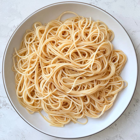 A plate of spaghetti noodles coated in a light olive oil glaze, ready to be servedの素材