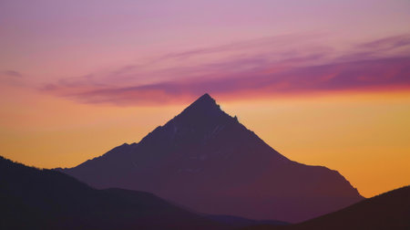 A majestic mountain peak basks in the warm glow of sunrise, its rugged silhouette against the colorful sky symbolizing strength and resilience in the face of the new day.の素材
