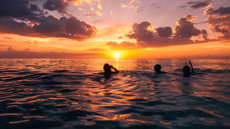 A serene sunset setting with silhouettes of snorkelers enjoying the last rays of light in calm, tropical watersの素材
