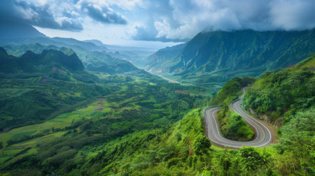 A winding mountain road snaking through lush greenery, offering breathtaking views of the valley below and the peaks above.の素材