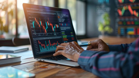 A businessman studying financial reports with colorful business graphs on a sleek laptop screen.の素材
