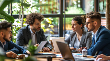 A team of businesspeople sitting around a table, examining a graph on a laptop screen.の素材