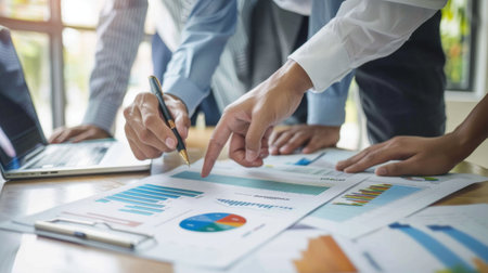 Two coworkers reviewing a printed business graph, with one pointing to a specific data point.の素材