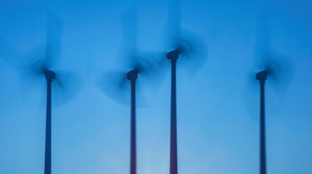 Shadows of wind turbines spinning against a clear blue sky, harnessing renewable energy from the sunの素材