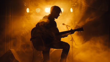 A musician playing a guitar, their silhouette cast against a wall illuminated by stage lightsの素材