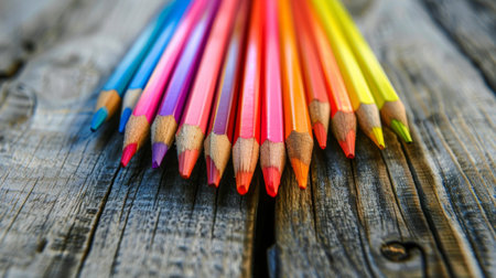 A set of colored pencils arranged in a heart shape on a wooden surfaceの素材